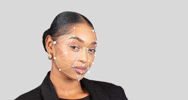 Yüzünde yüz tanıma programı gösterilirken resmi giyinmiş genç bir siyahi kadın kendinden emin duruyor. Arka plan az şekilli, ifadesini ve teknolojisini vurguluyor..