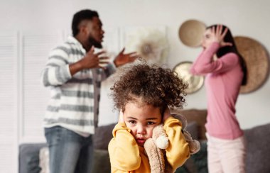 Uluslararası aileler kavga ediyor. Kulaklarını kapatan küçük kızına odaklan.