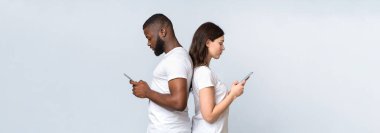 Gadget bağımlılığı ve ilişki sorunları. Akıllı telefonlarla sırt sırta verip kavga ettikten sonra birbirlerini görmezden gelen ırklar arası bir çift.