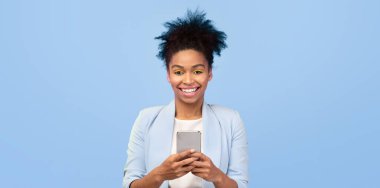 Harika bir uygulama. Mavi menekşe arkaplan, panorama, kopyalama alanı üzerinde akıllı telefon kullanan mutlu siyah kadın