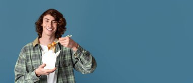 Paket yemek. Tek kullanımlık Çin eriştesi yiyen mutlu milenyum çocuğu, turkuaz arka planda. Boşluğu kopyala