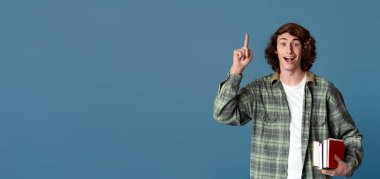 Kitapları ve notları olan heyecanlı genç bir öğrenci turkuaz arka plan üzerine parlak bir fikre sahip.