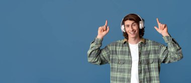 Gençlik kültürü konsepti. Kulaklıklı genç adam arka planda yukarıya bakıyor.