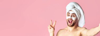 Man skin care and selfie. Millennial guy with mask on his face shows peace sign clipart