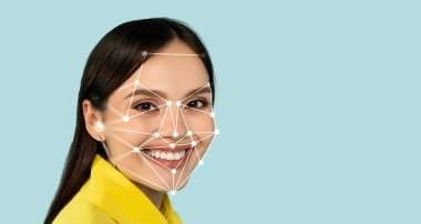 Dijital yüz tanıma sistemi yüzüne yerleştirildiğinde bir kadın parlak bir şekilde gülümsüyor. Arka plan, onun neşeli yüz ifadesini vurgulayan rahatlatıcı açık mavi..