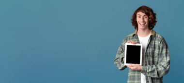 Kıvırcık milenyum adamı elinde tablet bilgisayarla renk arkaplanında boş bir ekran tutuyor. Tasarımınız için bir model.