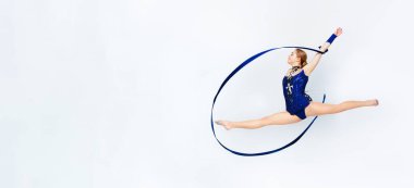 Yaylı güzel bir jimnastikçi beyaz arka planda havada sıçrama yapıyor.