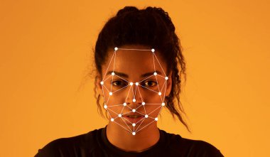 Yüzünde yüz tanıma işaretleri gösterilirken, Afro-Amerikalı kadın sıcak bir kehribar arka plana karşı duruyor, modern teknolojide yüz hatları ve ifadeleri vurguluyor.