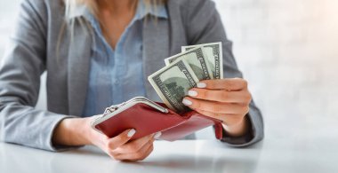 Karantina sırasında para kazanmak. Koruyucu maskeli kadın cüzdanına dolar koyuyor.