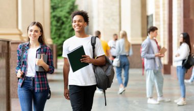Üniversite koridorunda yürüyen çok ırklı öğrenciler, ara verip iletişim kuruyorlar, boşluğu kopyalıyorlar.