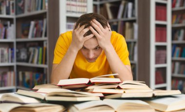 Kafkasyalı yorgun bir adam kafasını tutuyor ve kitap okuyor, sınavlara hazırlanıyor.