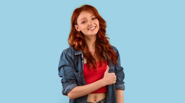 Gibi. Milenyum Kızı Sarı Stüdyo Arkaplanındaki Kameraya Gülümseyen Baş Parmakla Hareketli Kız. Panorama