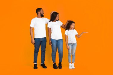 Üç aile üyesinin el fotografı ile boy uzunluğu ölçülmüş. Gülümseyen anne, baba ve kız gelişim çağında sarı turuncu arka planda izole bir şekilde duruyorlar.