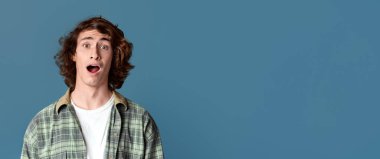 Renkli stüdyo arka planında bağıran şok olmuş genç adam.