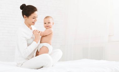 Mutlu bebek yatak, anne ile oynarken kameraya, boş alanı gülümseyen