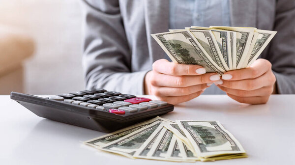 Планирование бюджета в кризисе. Женские руки рассматривают доллары, панораму
