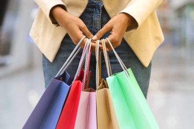 Alışveriş Konsepti. Tanımlanamayan Afrikalı Amerikalı kadın alışveriş merkezinde bir sürü renkli alışveriş çantasıyla dikiliyor.