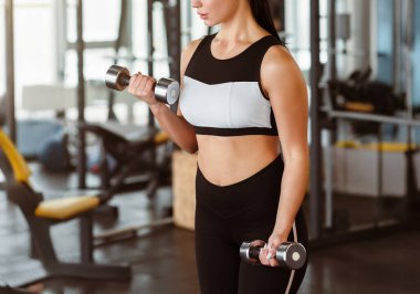 Güç sporları. Spor salonunda dambılları olan genç bir kadın.