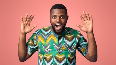 İnanamıyordum. Şaşırmış, elleri havada, mavi arka planda kameraya bakan, geleneksel Afrika kostümü giymiş siyahi bir adam. Duygusal Afrikalı Amerikalı genç adam stüdyoda poz veriyor.