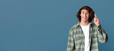 Mutlu genç adamın parlak bir fikri var, turkuaz arka planda EUREKA 'yı işaret ediyor.