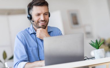 Yardım Hattı Destek Servisi. Modern ofiste dizüstü bilgisayarla çalışan yakışıklı erkek çağrı merkezi operatörü bilgisayar ekranına bakıyor, boş alan var.