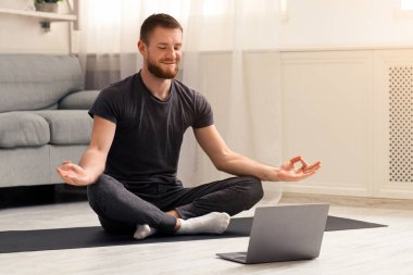 Karantinada sakin olun. Millennial elemanı antrenörle internetten laptopla meditasyon yapıyor. Boş alan.