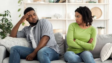 Sinirli siyahi adam ve kadın evdeki koltukta otururken kavga ettikten sonra birbirlerini görmezden geliyorlar, ilişki sorunları yaşıyorlar.