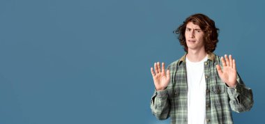 Memnun olmayan genç adam turkuaz arka planda inkar jesti yapıyor.