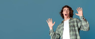 Panik ve stres konsepti. Turkuaz arka planda korkmuş yüz ifadesi olan yakışıklı bir genç.