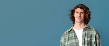 Turkuaz arka planda iğrenç bir ifadesi olan genç adam.