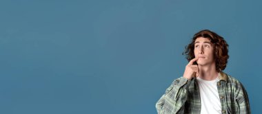 Düşünceli genç adam turkuaz arka plan ve fotokopi alanı üzerine kafa yoruyor. Panorama