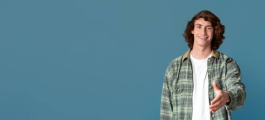 Selamlama konsepti. Gülümseyen beyaz ergen, turkuaz arka planda el sıkışmak için elini uzatıyor.