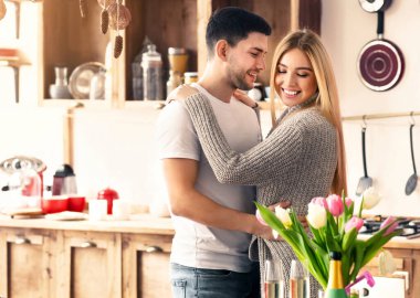 Birlikte güzel bir hafta sonu geçiriyoruz. Gülümseyen karı koca, mutfakta sarılıyorlar, boşluk.