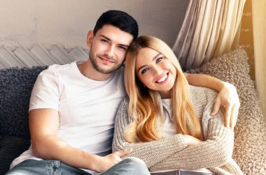 Gülümseyen milenyum eşleri evdeki kanepede kucaklaşıyorlar, boşluğu kopyalıyorlar.