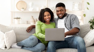 Hafta sonu eğlencesi. Evli siyah çift evde dizüstü bilgisayar kullanıyor oturma odasında dinleniyor, film izliyor, mekanı kopyalıyor.