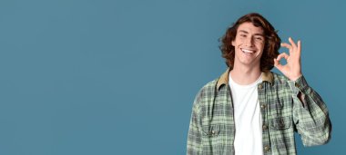 Anlaşma jesti. Mutlu beyaz adam turkuaz arka planda iyi bir hareket gösteriyor.