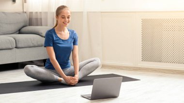 İnternetteki yoga pratiği. Evde dizüstü bilgisayarın yanında meditasyon yapan genç bir kadın.