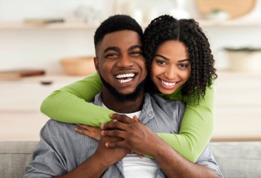 Afrika kökenli Amerikalı çiftin evde sarılıp kameraya baktıkları ve karantinayı birlikte geçirdikleri portre.