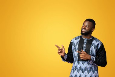 Geleneksel Afrika kıyafetleri içinde yakışıklı bir zenci fotokopi odasını pembeye çeviriyor. Gülümseyen Afrikalı Amerikalı genç adam renkli arka plan, stüdyo çekimi ve panorama için harika bir teklif sunuyor.