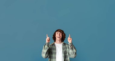 Özel fiyat. Heyecanlı genç adam renk arkaplanındaki boşluğu işaret ediyor