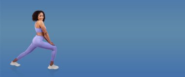 Lavanta rengi atletizm seti giyen bir kadın esneme egzersizi yapıyor, vücudunu ve esnekliğini gösteriyor. Temiz mavi arka plan onun hareketlerine odaklanmasını sağlar..