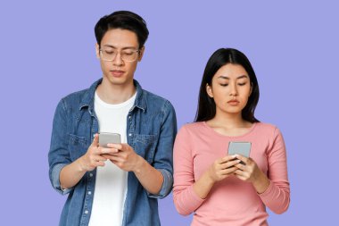 Asyalı çift izolasyon sırasında cep telefonu kullanıyor, gri arkaplan