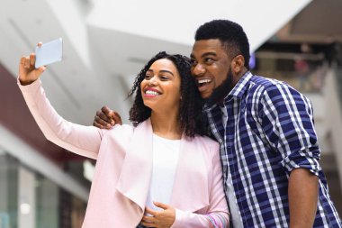 Başarılı bir alışveriş sonrası mağazada selfie çeken mutlu Afrikalı çift.