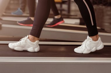 Kardiyo çalışması. Spor salonunda koşu bandında tanınmayan bir kadın, yakın plan.