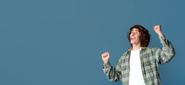 Zafer ve başarı kavramı. Çekici genç adam heyecanlanıyor ve turkuaz arka planda EVET işareti yapıyor.