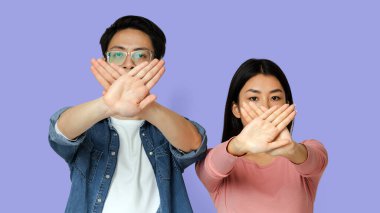 Biz konuşmayız. Genç Asyalı çift avuçlarını çapraz tutarken ağızlarına, gri arka planda