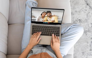 Bir insan koltuğa rahatça oturur ve gülümseyen bir çiftle bilgisayarındaki bir video görüşmesine bağlanır. Mekan sıcak, davetkar bir oturma odası, dostane bir atmosfer yaratıyor..