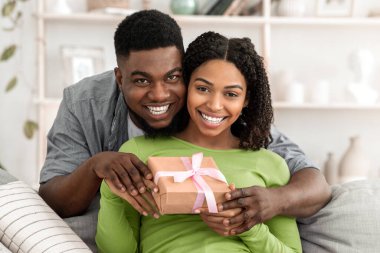 Evdeki koltukta birbirlerine aşık siyah bir çiftin portresi, kameraya bakıyor ve gülümsüyor, boşluğu kopyalıyor.