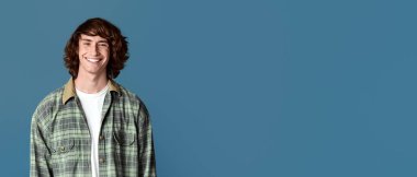 Kıvırcık saçlı yakışıklı, arka planda gülümseyen.