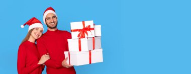 Noel hediyeleri. Mavi Stüdyo Arkaplanında Hediye Kutuları Olan Mutlu Genç Çift, Kış Tatillerinde Gülümseyen Adam ve Kadın, Xmas Kutlamasının tadını çıkarıyor, Boşluğu Kopyalamak